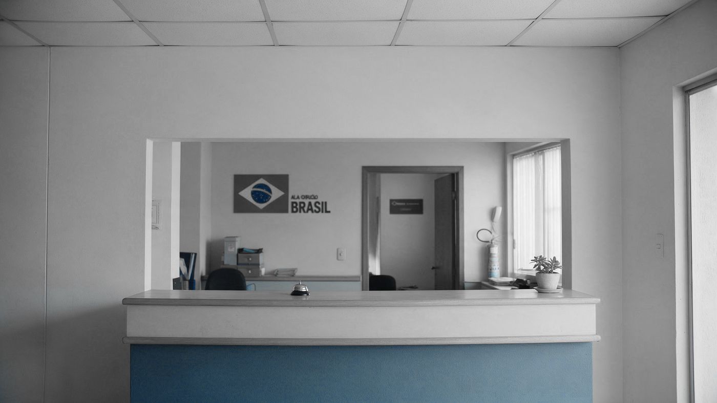 Recepção de uma pequena empresa com a porta do escritório do dono ao fundo